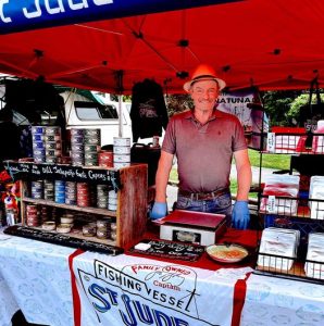 Joe Malley stands with cans of St Jude tuna at a market table.