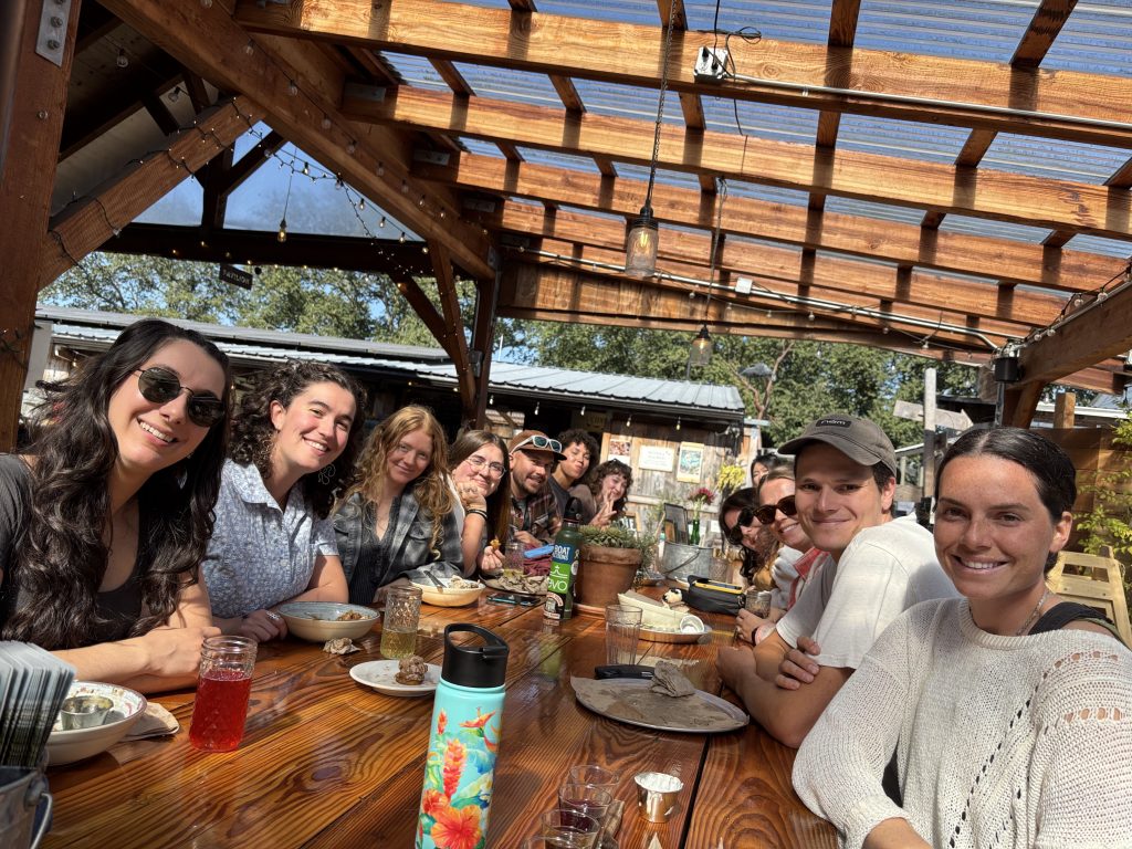Seated at a long banquet table, fellows smile at the camera