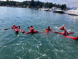 A group of people wearing red survival suits floating in the water