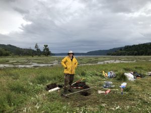 Carrie Garrison-Laney stands in a marsh with research tools scattered around her.