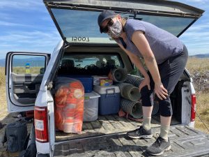 A woman standing on a tailgate of a truck with coolers and crab traps in the back.