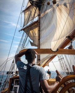 A man on a tall ship looking up at the sails