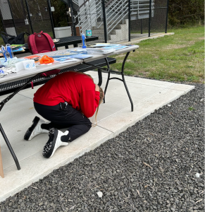 Person covering their head while kneeling under a table