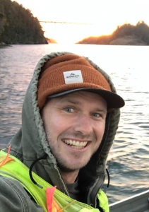 Stuart Thomas on a boat, water and islands behind him.