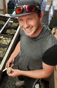 Stuart Thomas shucks oysters and smiles at the camera