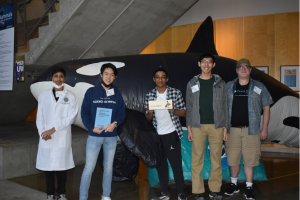 a group of high school students standing in front of an inflatable orca whale