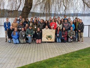 2023 Trappers' Summit attendees gathered around a green crab banner.