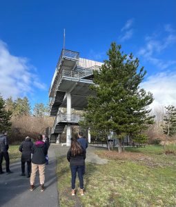 People stand in front of a vertical evacuation tower
