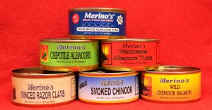 A stack of canned seafood with labels including smoked Chinook, chipotle albacore and minced razor clams. 